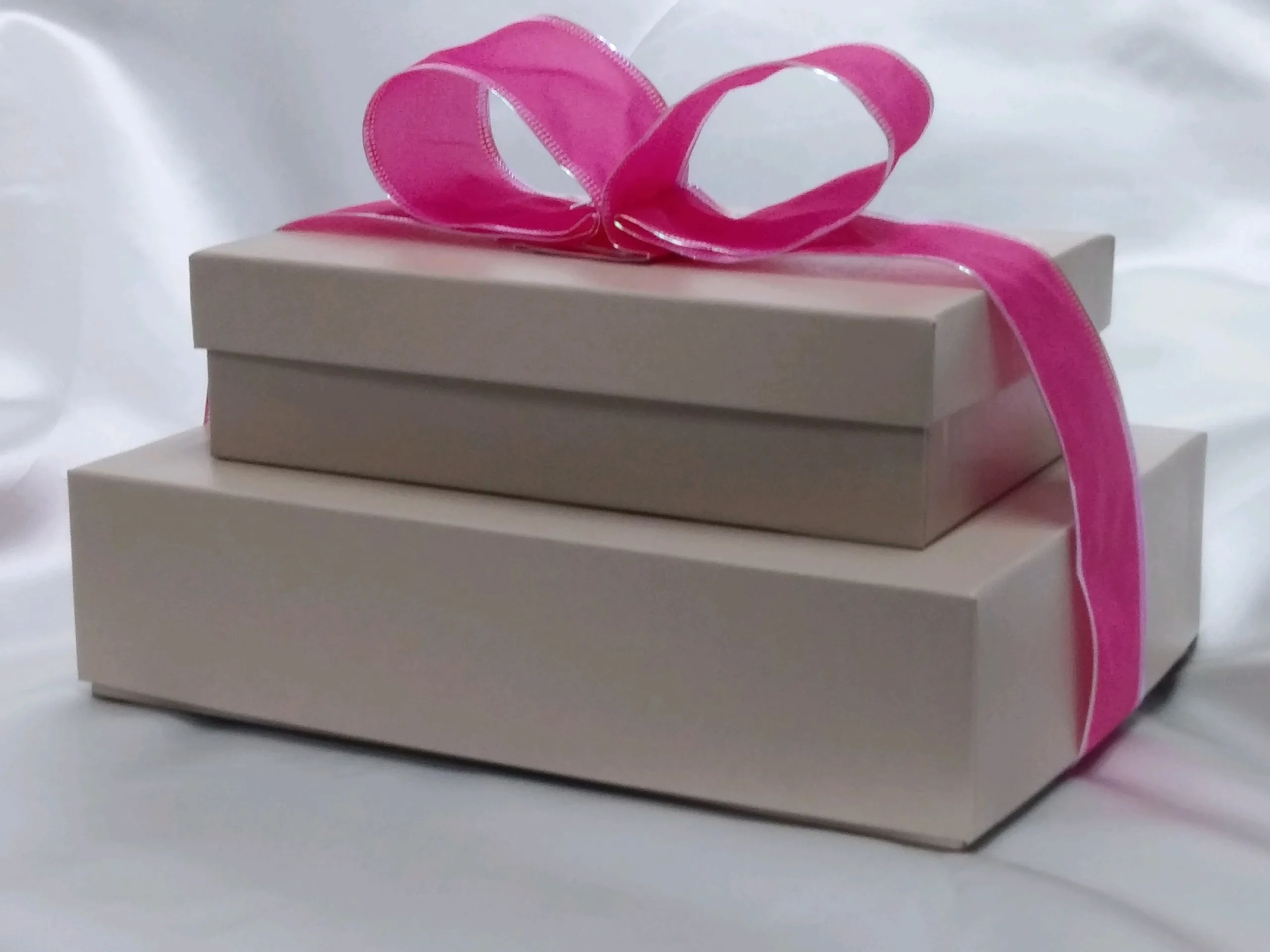 two white boxes with pink ribbon on them
